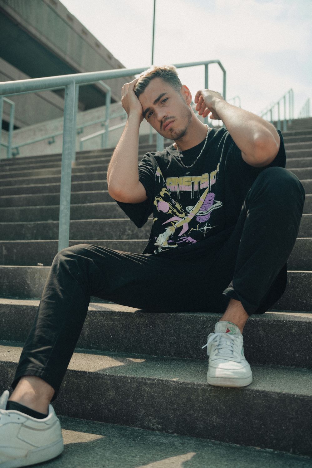 Model wearing the TD Studio Grey Hoodie seated on concrete steps